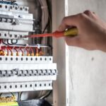 Elektriker som skruvar i elskåp