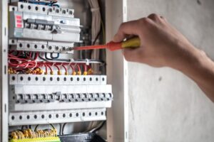 Elektriker som skruvar i elskåp